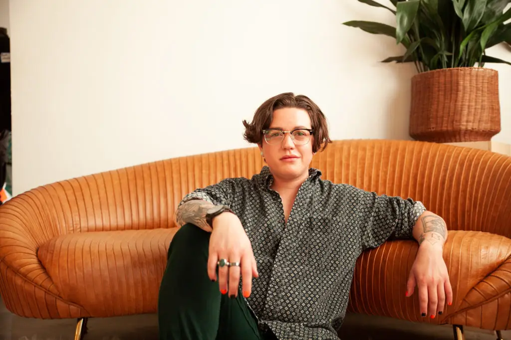 ftm transgender transmasc transman sitting on floor by an orange couch. cover image for article about ftm bottom growth