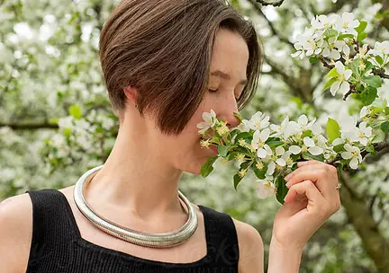 Person smelling white flowers on a branch