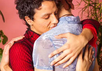 Close up of two people wearing colorful clothes embracing