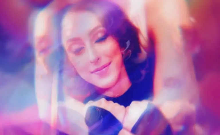 Person with closed eyes embraced from behind, surrounded by dreamy pink and purple light effects