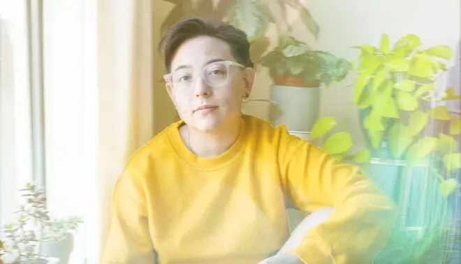 Person in a yellow sweater sitting near plants