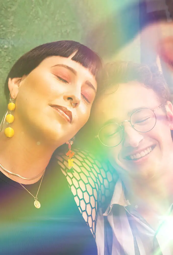 two people standing closely together with their eyes closed smiling